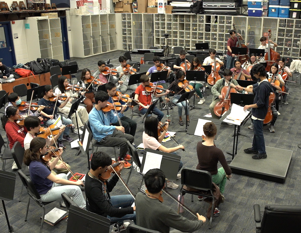 Nikhil Murali conducting an orchestra during a rehearsal
